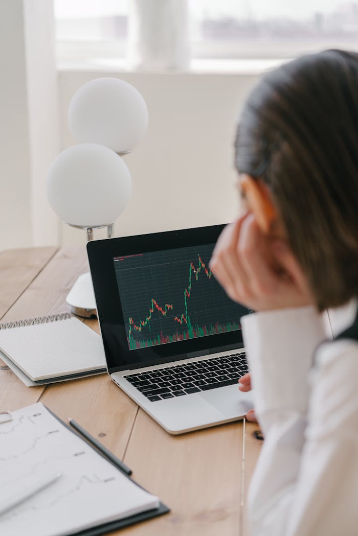 A person analyzing stock market data on a laptop in an office setting.